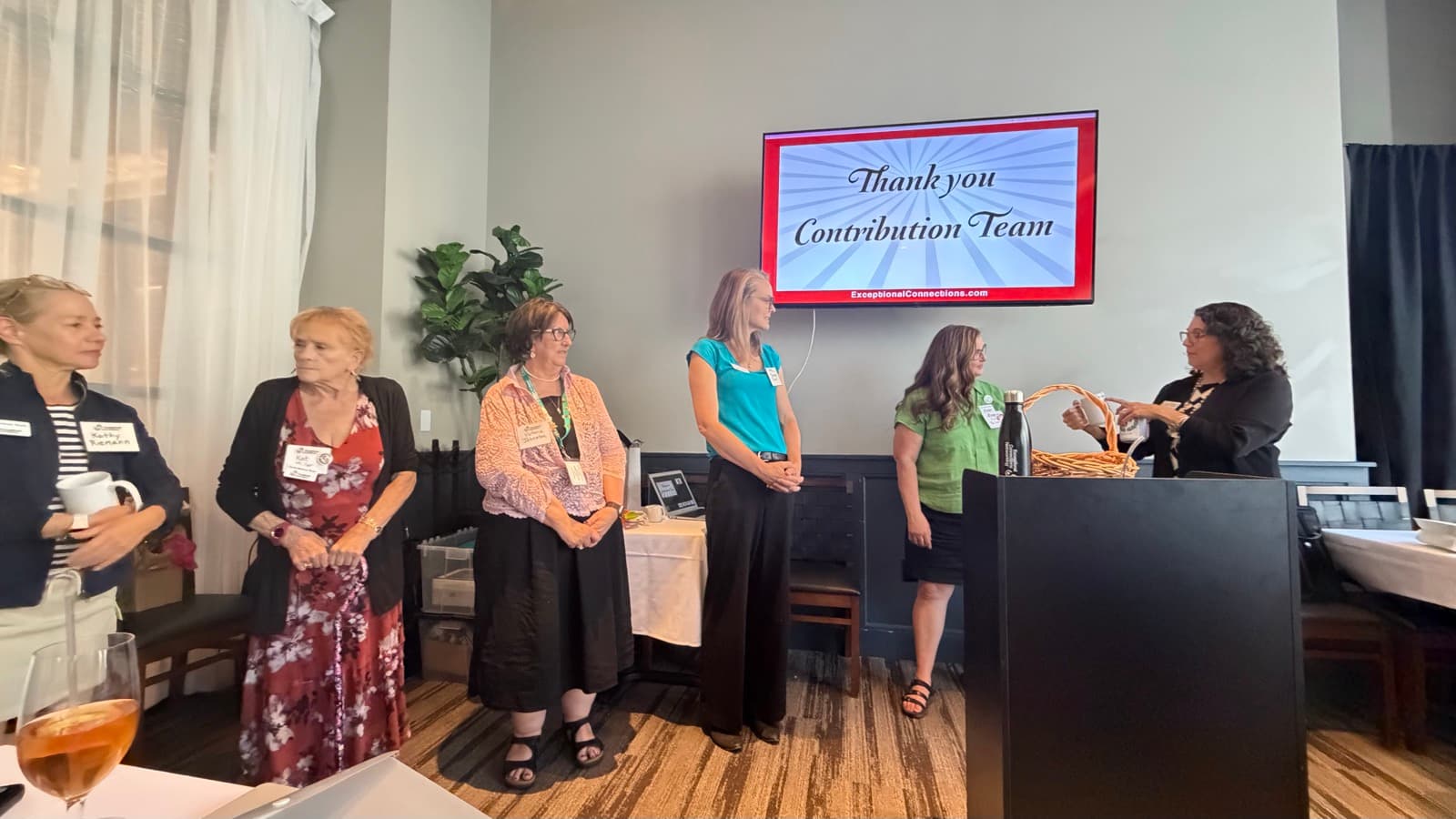 Cyndi O'Neill-Dady thanking the Exceptional Connections Contribution Team as members stand at the front of the room