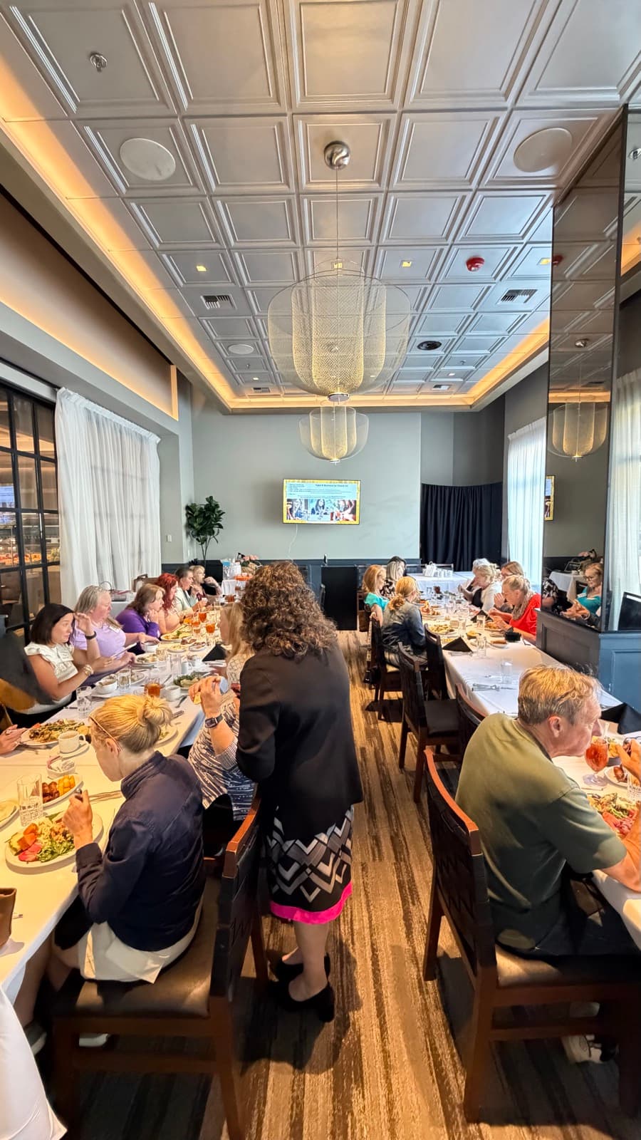 A wide view of the July Exceptional Connections luncheon room in Lynnwood, with members seated at long tables